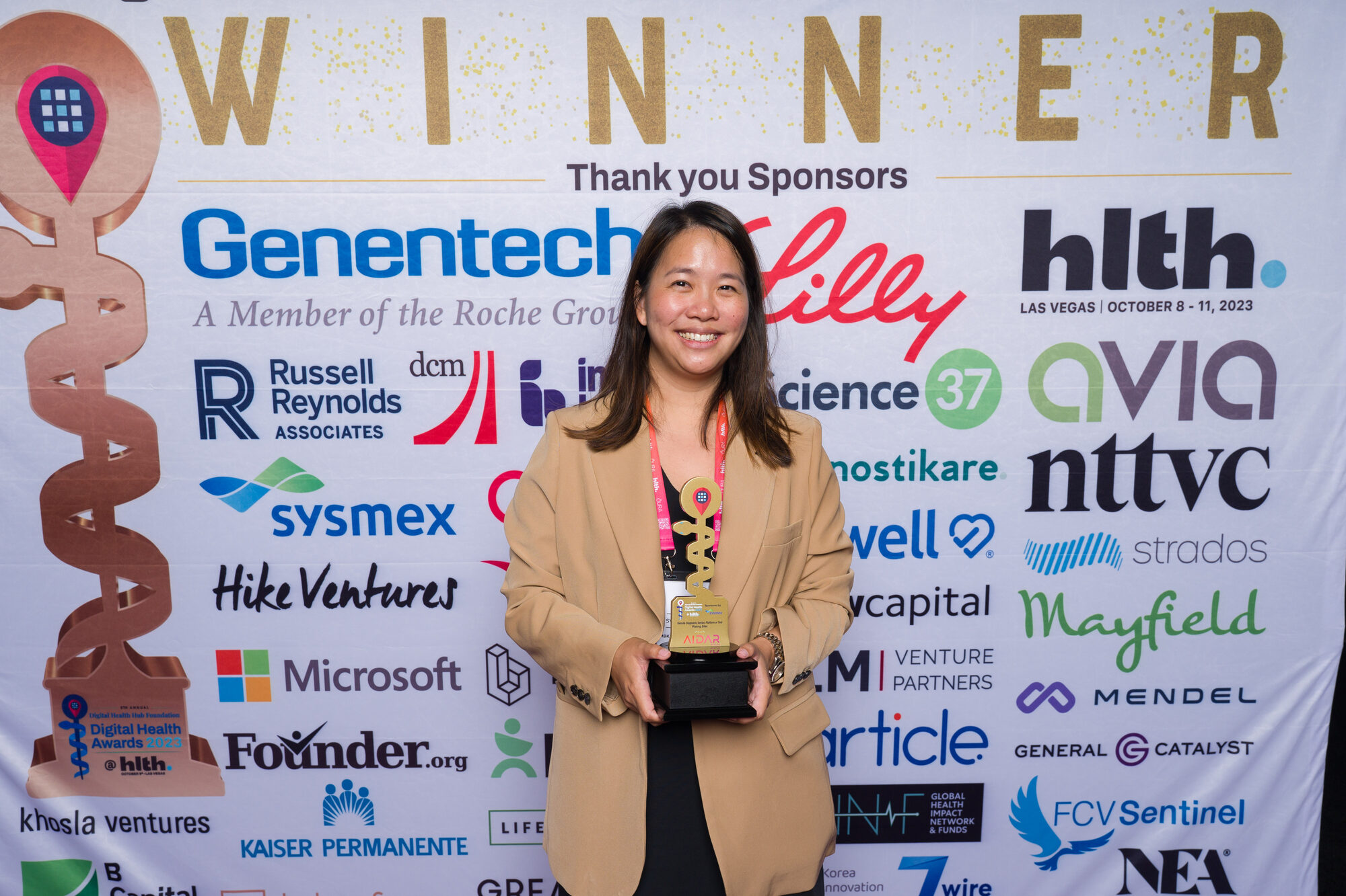AIDAR Health accepting a Digital Health Award trophy at HLTH in front of the winners backdrop.